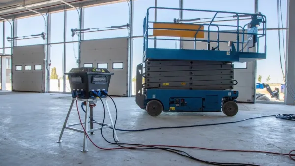 Load balancer oplaadstation van RECO aangesloten op een elektrische schaarhoogwerker