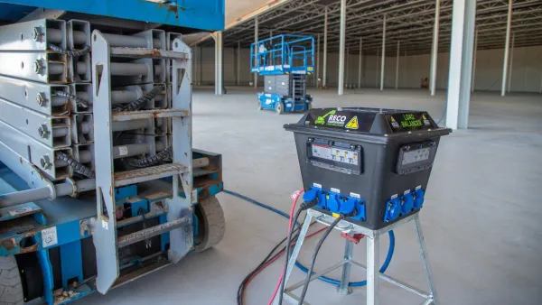 Load balancer oplaadstation van RECO aangesloten op een elektrische schaarhoogwerker op de bouwplaats