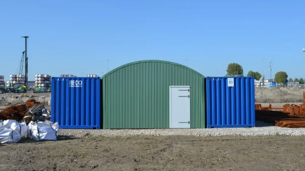 Varianthal van 7,8 meter breed met RECO-containers op een bouwplaats, ingericht als tijdelijke werkplaats of opslagruimte.