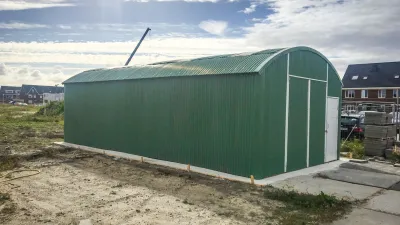 Groene varianthal van 7,8 meter breed als tijdelijke werkplaats of opslagruimte op een bouwlocatie.