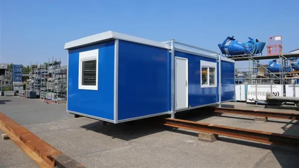 Vrijstaande blauwe RECO bouwkeet met keuken op een buitenterrein.