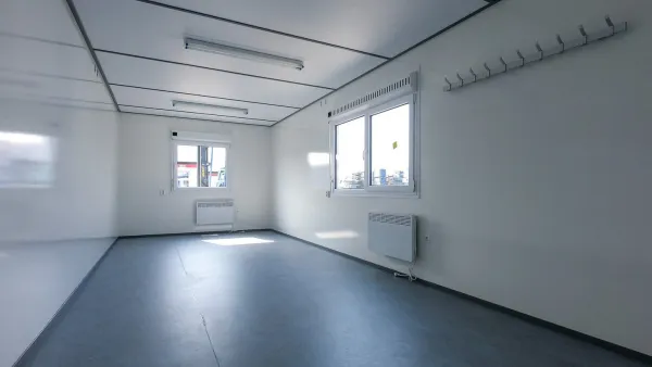 Interieur van een vrijstaande bouwkeet met ramen, verlichting en elektrische verwarming.