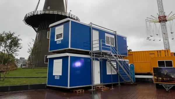 Gestapelde blauwe RECO bouwketen met buitentrap op een tijdelijke locatie.