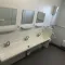 Wastafelruimte in toiletunit met drie kranen en spiegels.