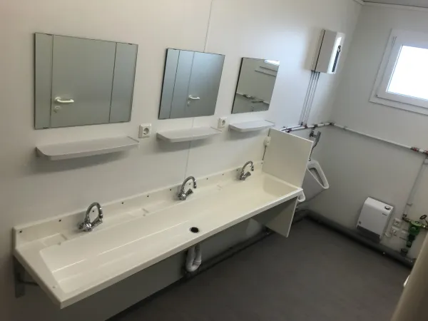 Wastafelruimte in toiletunit met drie kranen en spiegels.