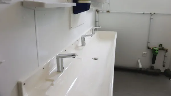 Wastafels met kranen in sanitairunit met 2 douches en 2 toiletten.