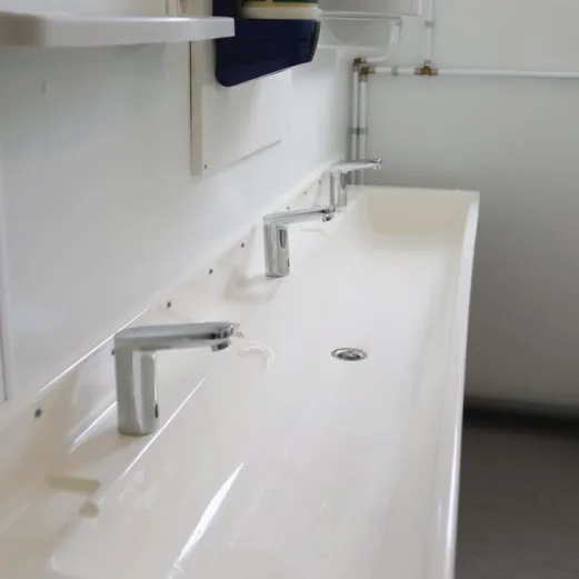 Wastafels met kranen in sanitairunit met 2 douches en 2 toiletten.