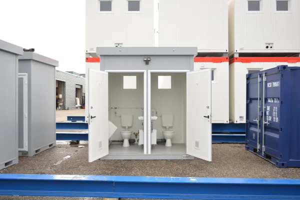 Sanitairunit met geopende deuren en toiletten aan de binnenzijde.