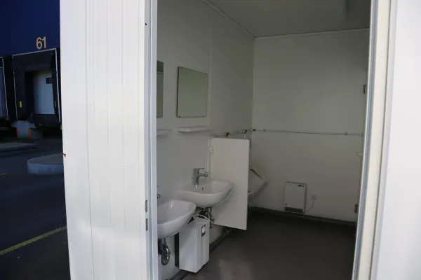 Interieur van toiletunit met wastafels, spiegels en elektrische verwarming.