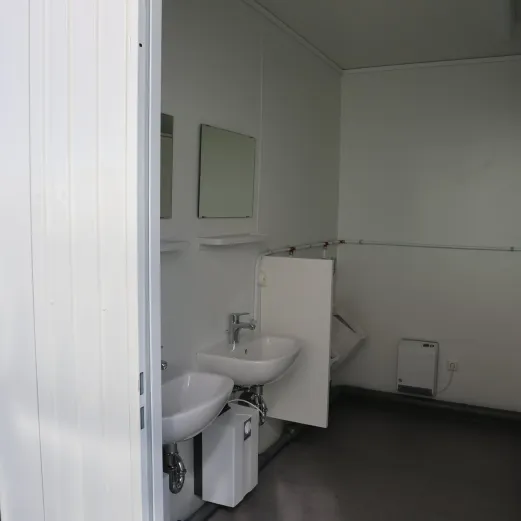 Interieur van toiletunit met wastafels, spiegels en elektrische verwarming.