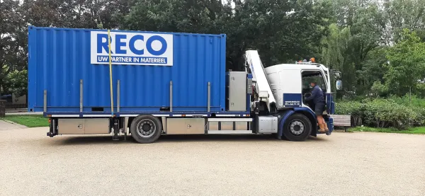 RECO vrachtwagen met blauwe 10 ft container tijdens transport