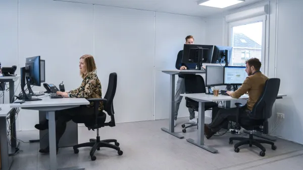 Verstelbare zit-sta-bureaus in gebruik door medewerkers in een tijdelijke kantoorunit.