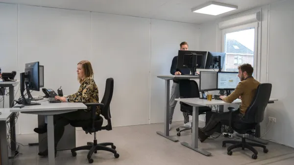 Medewerkers aan verstelbare zit-sta-bureaus in een tijdelijke kantoorruimte
