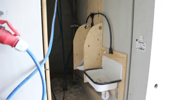 Tijdelijke wateraansluiting met wastafel en leidingen op een bouwlocatie